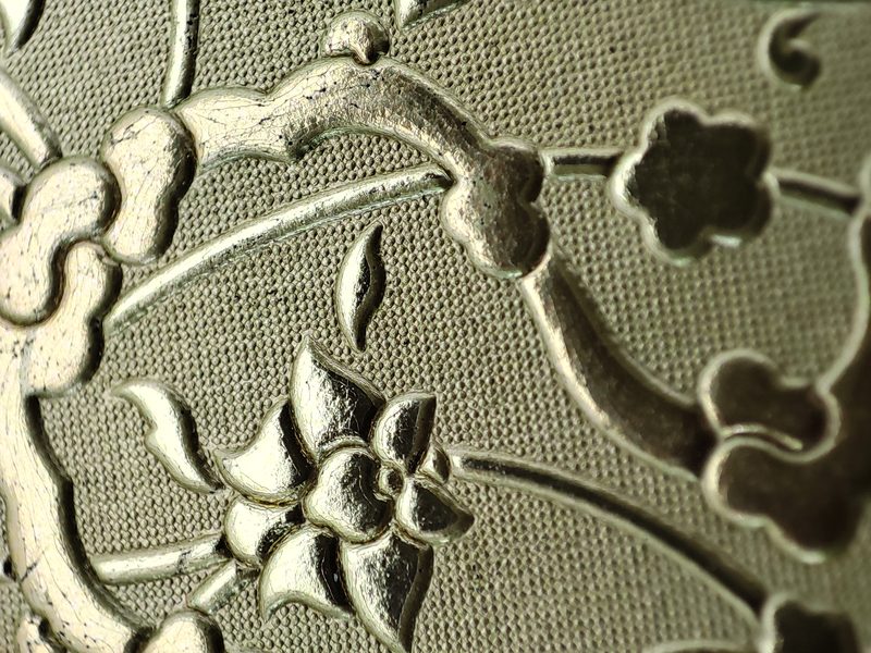 Macro detail of deep floral relief embossing on leather, showing clean shoulders