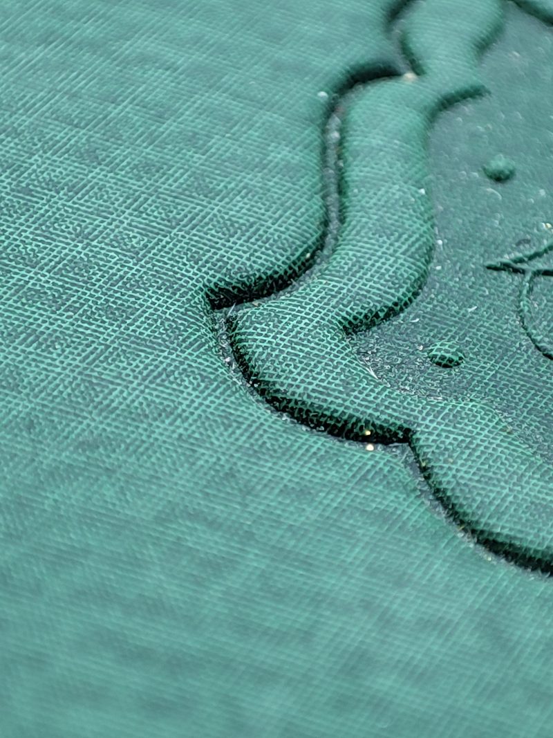 Deep blind relief on teal leather showing clean shoulders