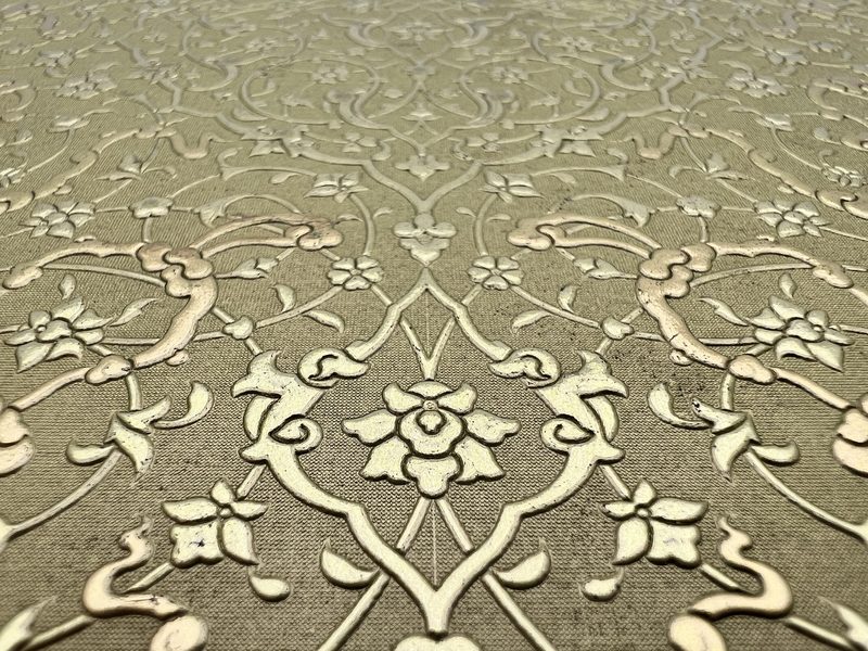 Macro of gold foil floral scrollwork on leather